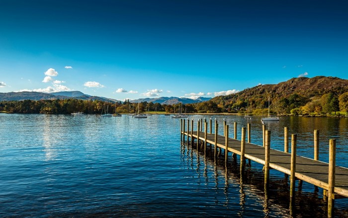 Wooden pier on a lake with sailboats and mountains