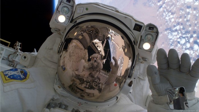 Astronaut in a spacesuit reflecting Earth in helmet