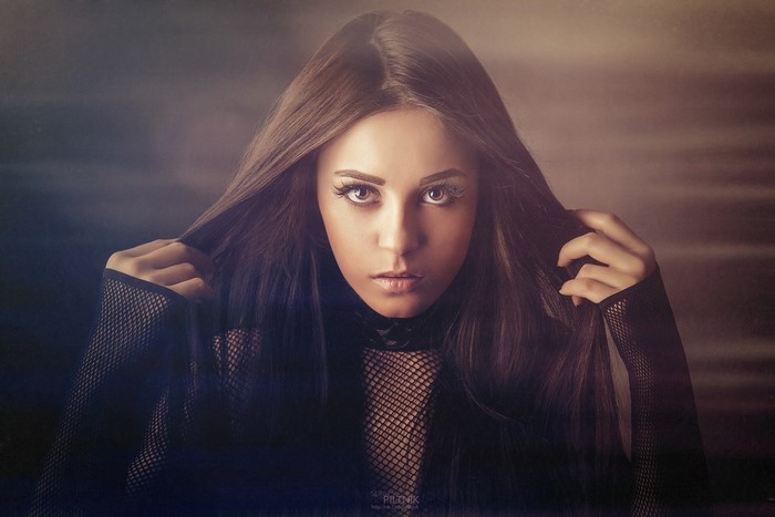 Woman with long brown hair, hands in hair, portrait