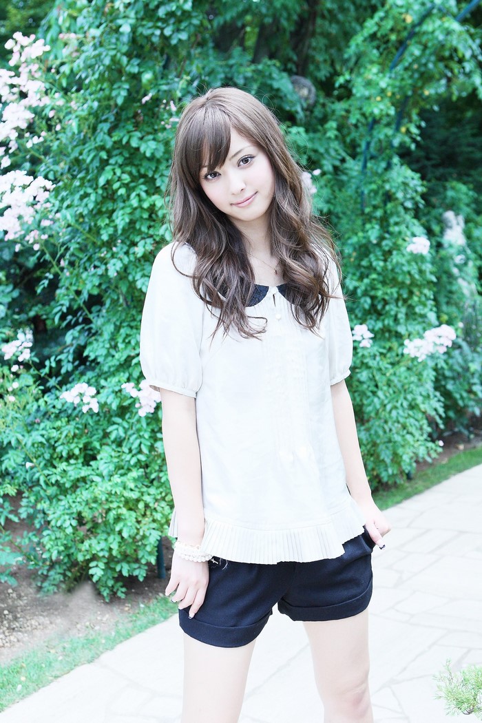 Sasaki Nozomi wearing a white blouse and black shorts outdoors