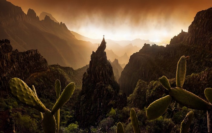 Man on a rocky peak in a mountain valley at sunset