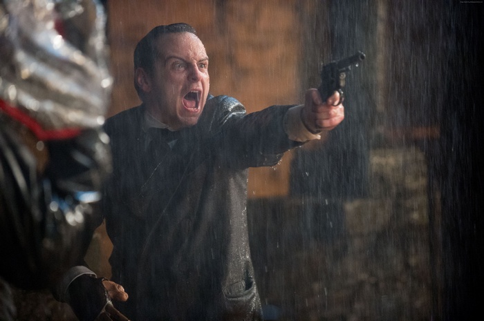 Andrew Scott as Victor Frankenstein holding a gun in the rain