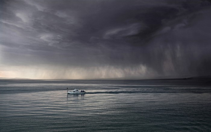 Boat sailing on a stormy sea under dark clouds
