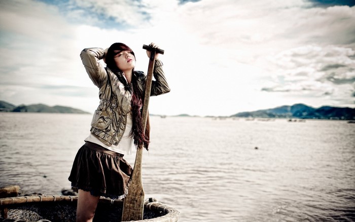 Woman in boat with oar by the sea