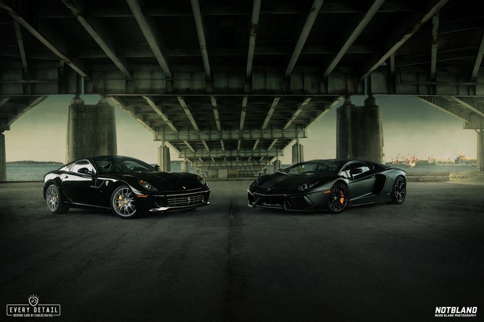 Black Ferrari and Lamborghini parked under a bridge