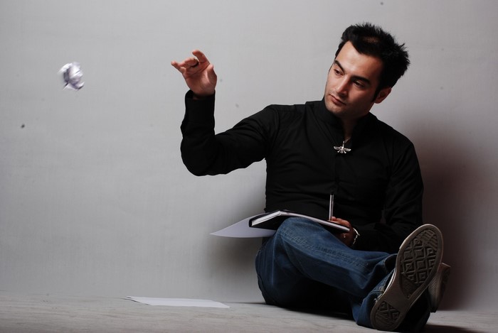 Man sitting on floor throwing paper