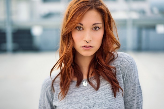 Woman with red hair and nose ring wearing a grey sweater