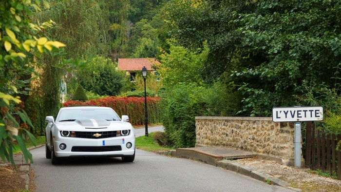 White Chevrolet Camaro driving past L'Yvette sign