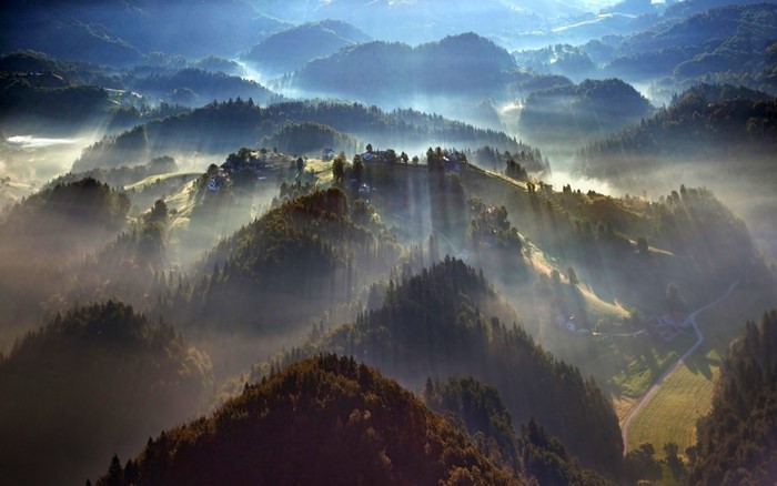 Misty mountain village at sunrise with sunbeams