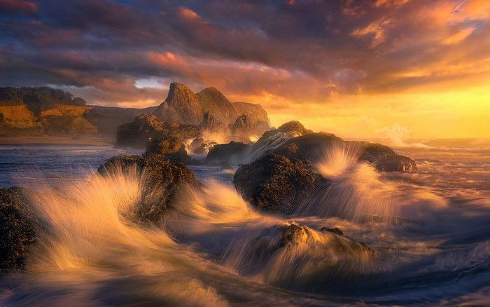 Waves crashing on rocks at sunset