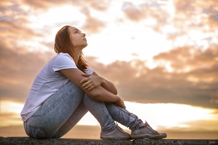 Woman sitting on a ledge at sunset