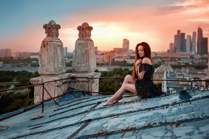Woman with red hair sitting on a rooftop at sunset