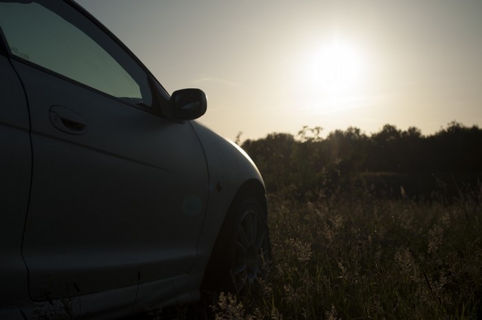 Car parked in a field at sunset
