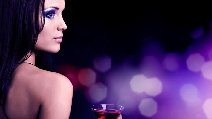 Woman with blue eyeshadow holding a cocktail