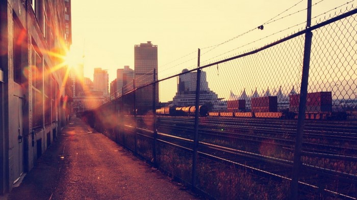 Sunset over a rail yard with cityscape and train cars