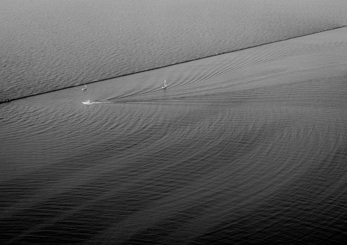 Boats sailing on the water with a breakwater