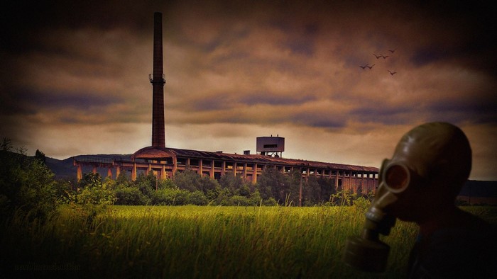 Abandoned factory with gas mask person at sunset