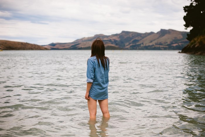 Woman standing in water with mountains in background