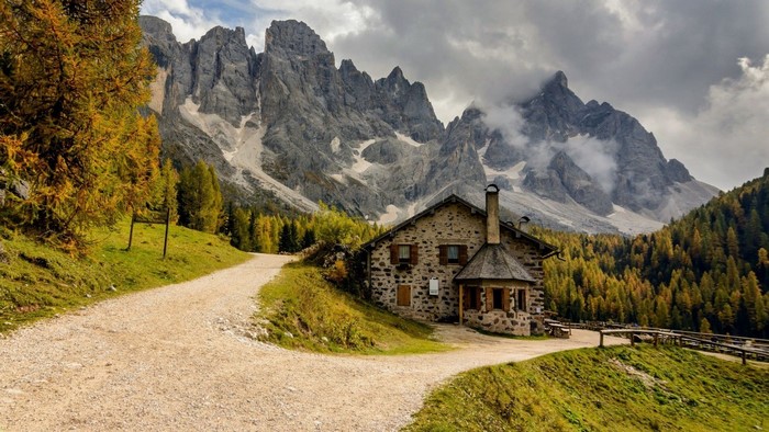 Stone house in autumn mountains with a dirt road