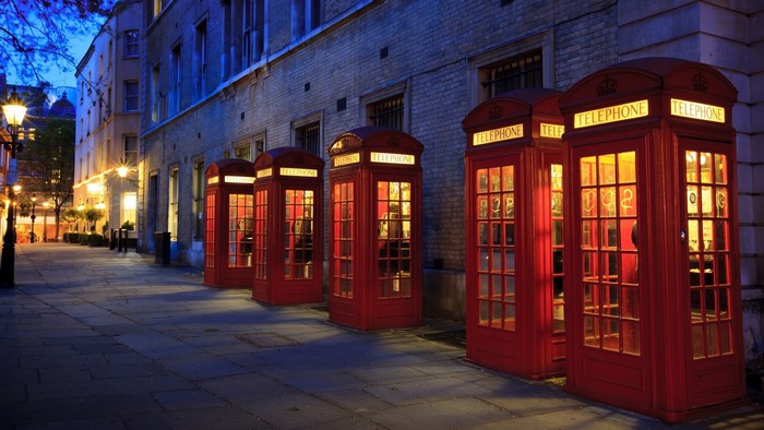 Red telephone boxes on a street at night