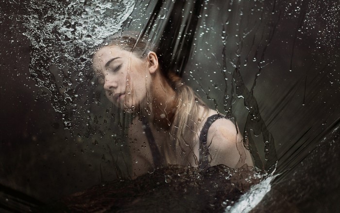 Woman behind wet plastic sheet with water splashes