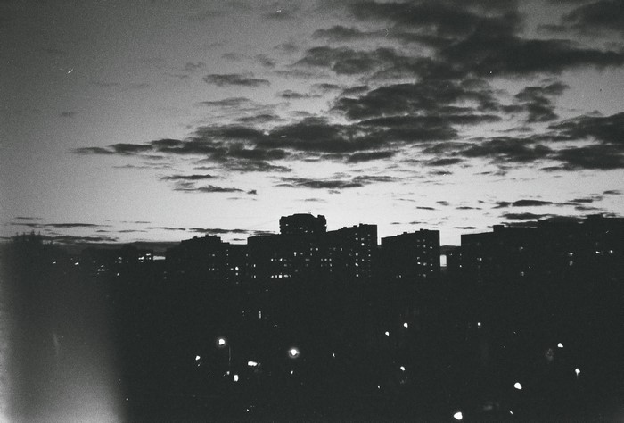 Monochrome cityscape at dusk with cloudy sky