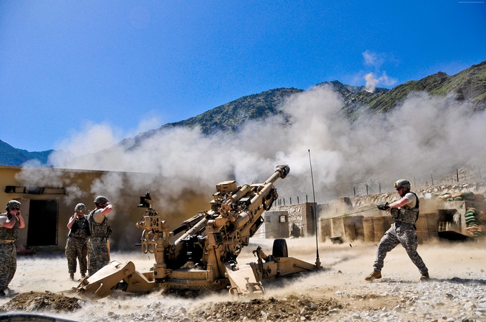 US Army soldiers firing artillery in a mountainous region