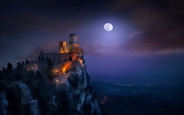 Castle on a cliff at night under the moon