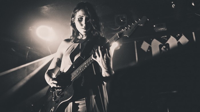 Chelsea Wolfe performing on stage with guitar