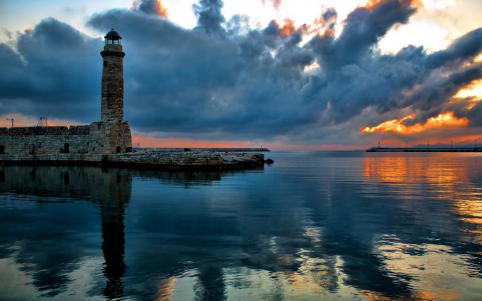 Lighthouse at dusk with dramatic clouds over the sea