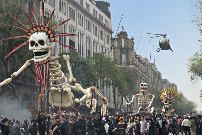 Day of the Dead parade with giant skeletons and helicopter