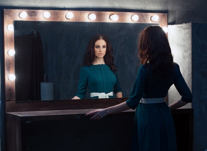 Woman in blue dress looking in a mirror