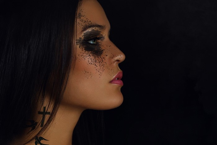 Woman with dark makeup and cross tattoo