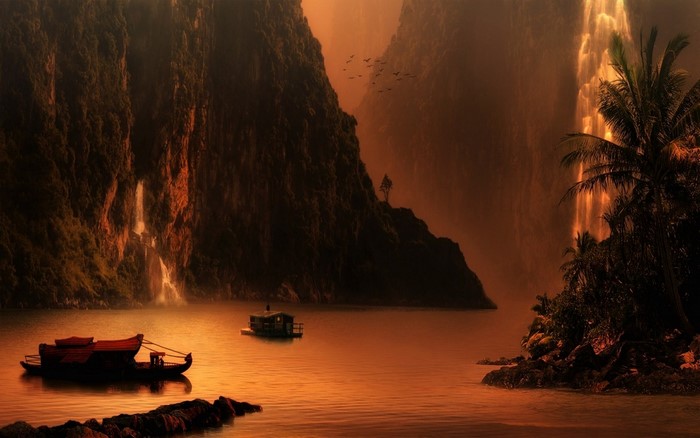 Boats on a lake with waterfalls and mountains