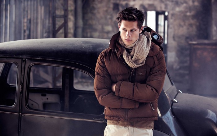 Man in brown jacket and scarf by vintage car