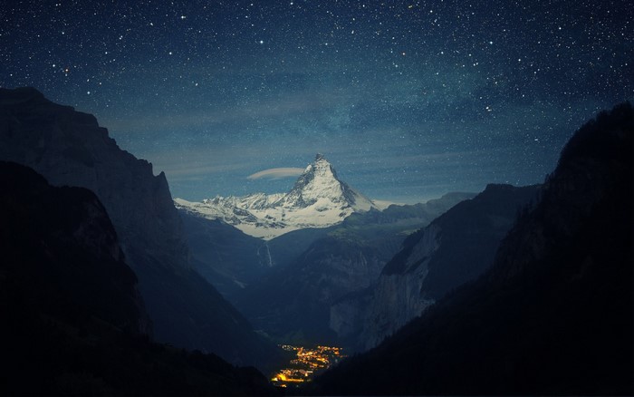 Matterhorn mountain at night with stars and a village