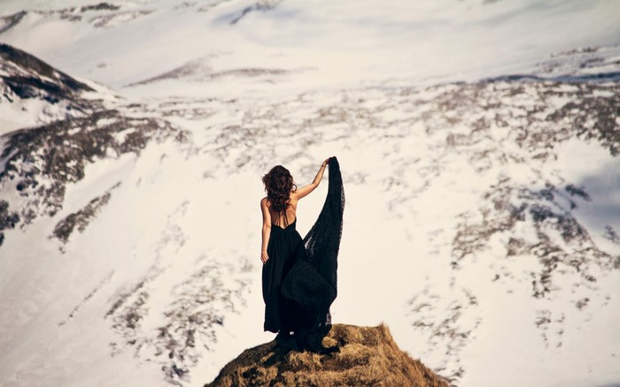 Woman in black dress on snowy mountain peak
