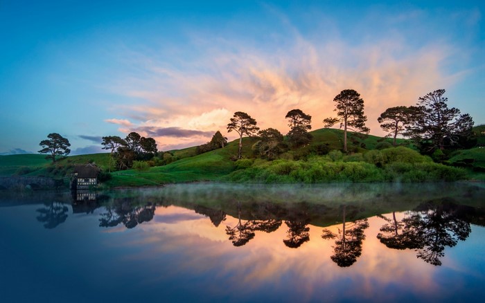 Hobbiton landscape with trees and lake at sunrise