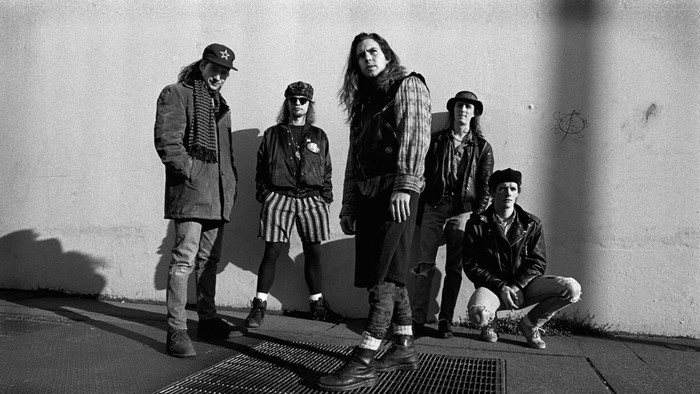 Pearl Jam band members posing against a wall