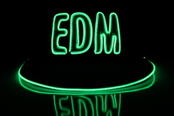 Green neon sign spelling EDM with reflection
