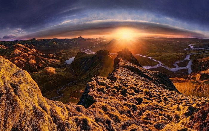 Panoramic mountain valley at sunrise with sun rays