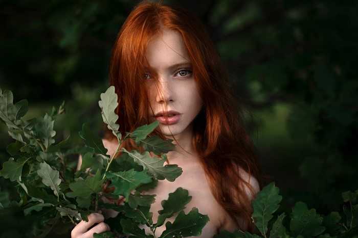 Redhead woman with green leaves in forest