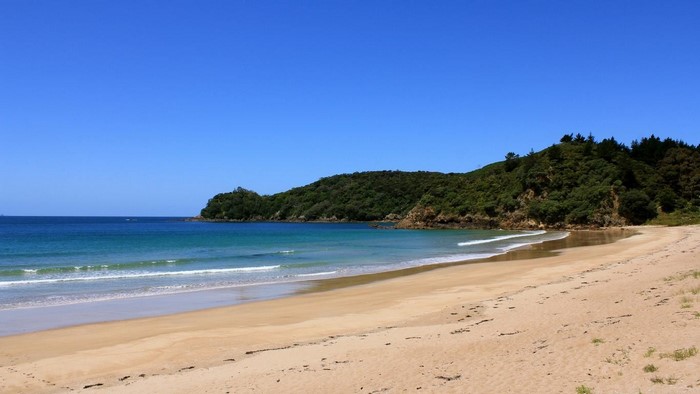 Sandy beach with green hills and blue ocean