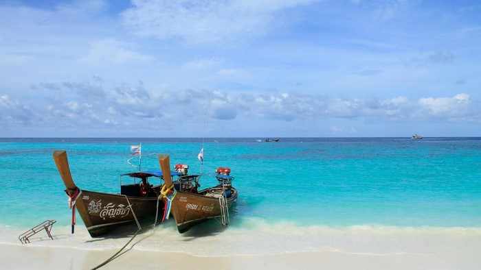 Two long tail boats on a tropical beach with turquoise water
