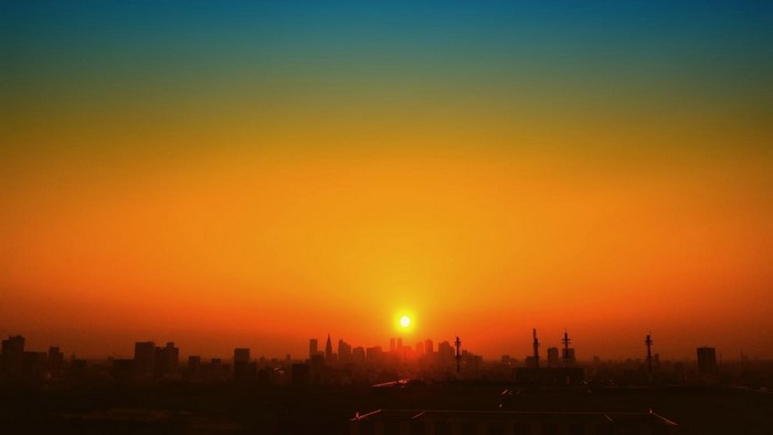 Sunset over a city skyline with orange and blue sky