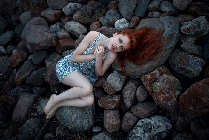 Redhead woman lying on rocks