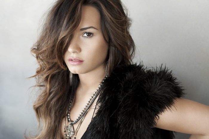 Demi Lovato wearing a black feathered vest and necklaces