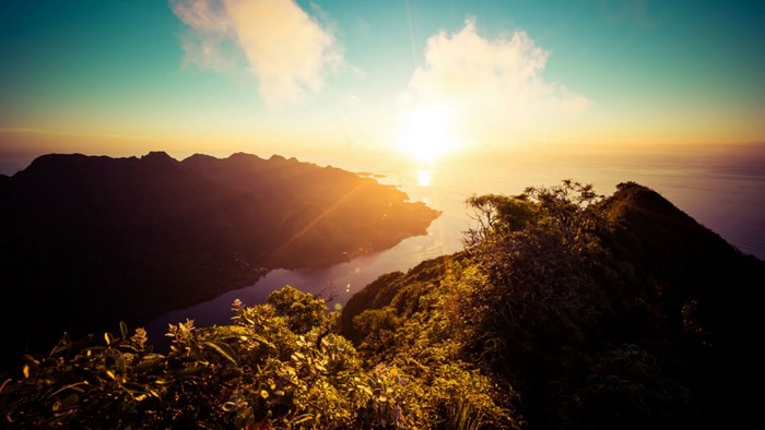 Sunrise over a mountainous coast with ocean and clouds
