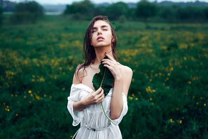 Woman holding a leaf in a grassy field