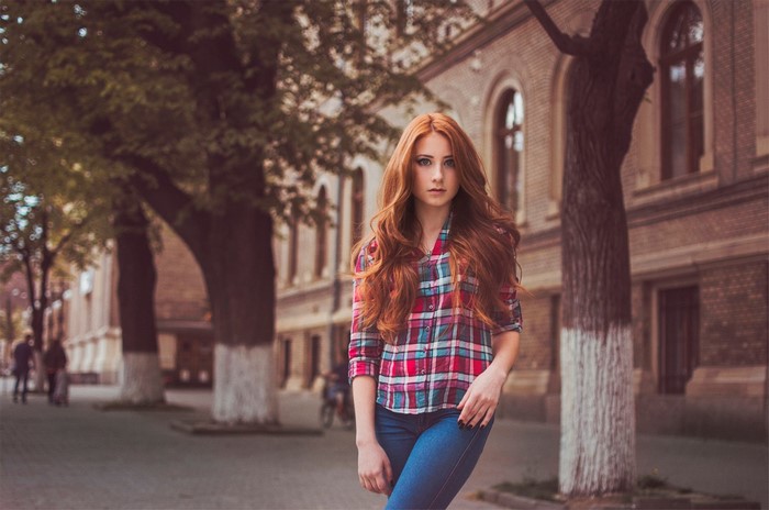 Redhead woman in plaid shirt and jeans on street